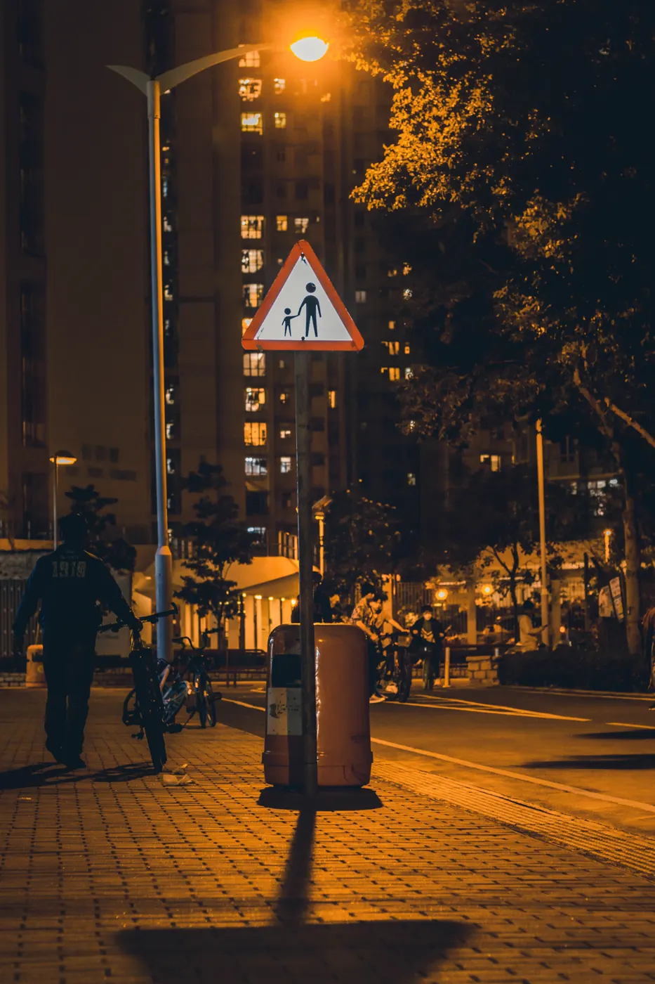 香港夜晚一條街道，路燈同行人路標誌